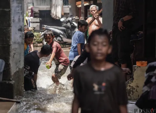 Anak-anak bermain air genangan banjir yang melanda kawasan RT 03, RW 06, Jati Padang, Pasar Minggu Jakarta Selatan, Jumat, 31 Oktober 2025. (Sumber: Poskota/Bilal Nugraha Ginanjar)