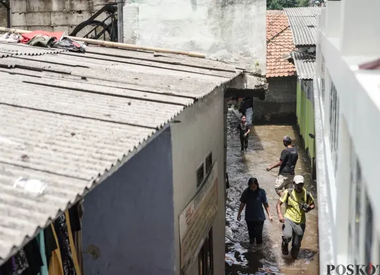 Warga berjalan menerobos banjir yang melanda kawasan RT 03, RW 06, Jati Padang, Pasar Minggu Jakarta Selatan, Jumat, 31 Oktober 2025. (Sumber: Poskota/Bilal Nugraha Ginanjar)