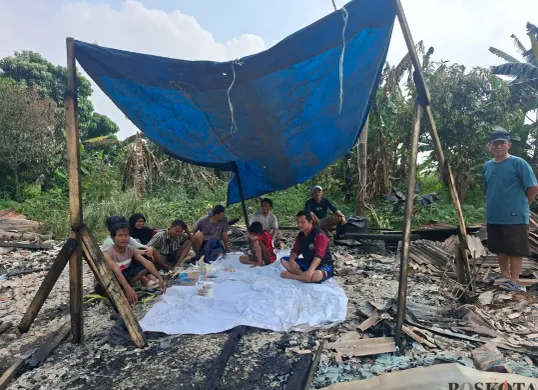Para pemilik lapak kayu kusen yang terbakar masuh bertahan mendirikan lapak dengan terpal yang tersisa dari kebakaran di lokasi kejadian. (Sumber: Poskota/Angga Pahlevi)