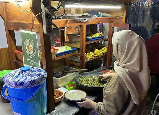 Hanifah, pedagang ayam penyet sambel ijo di kawasan Palmerah, Jakarta Barat, saat sedang melayani pembeli, Rabu, 10 September 2025. (Sumber: POSKOTA | Foto: Pandi Ramedhan)