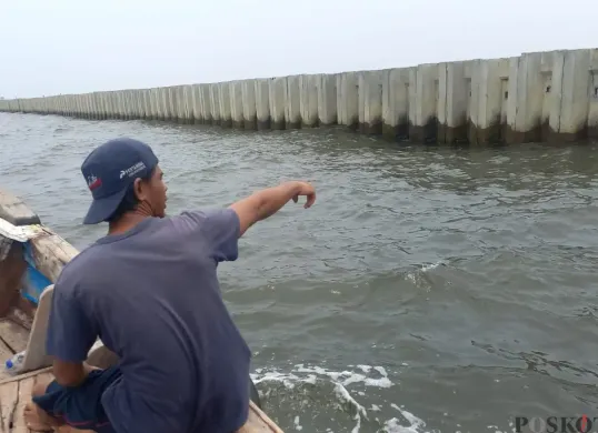Salah seorang nelayan menunjukkan Tanggul Beton di perairan Cilincing, Jakarta Utara, Kamis, 11 September 2025. (Sumber: Poskota/Muhammad Tegar Jihad)