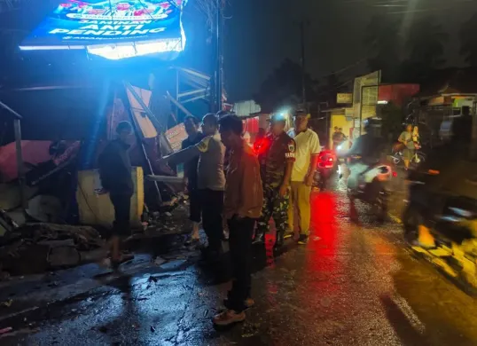 Petugas meninjau lokasi rubuhnya papan Reklame hingga menimpa tiga kios pedagang kali lima di Jalan Raya Sudimampir, Bojonggede, Kabupaten Bogor. (Sumber: Dok. Polsek Bojonggede)