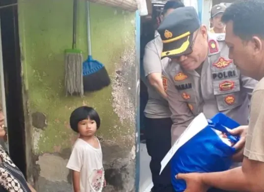 Kapolsek Beji Kompol Josman Harianja blusukan bersama anggota membagikan bantuan paket sembako ke warga ibu-ibu yang tinggal di dalam gang sempit Kelurahan Beji, Kota Depok, langsung tersenyum bahagia. (Sumber: Poskota/Angga Pahlevi)