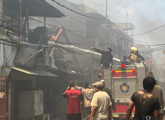 Petugas pemadam kebakaran hingga warga berupaya memadamkan api kebakaran rumah di Gang Langgar 1 RW 06, Kelurahan Tangki, Kecamatan Tamansari, Jakarta Barat, Minggu, 28 September 2025. (Sumber: Poskota/Pandi Ramedhan)