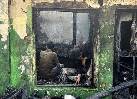 Warga mencari barang di tengah puing-puing rumahnya yang hangus terbakar di Gang Langgar, Kecamatan Tamansari, Jakarta Barat, Minggu, 28 September 2025. (Sumber: POSKOTA | Foto: Pandi Ramedhan)