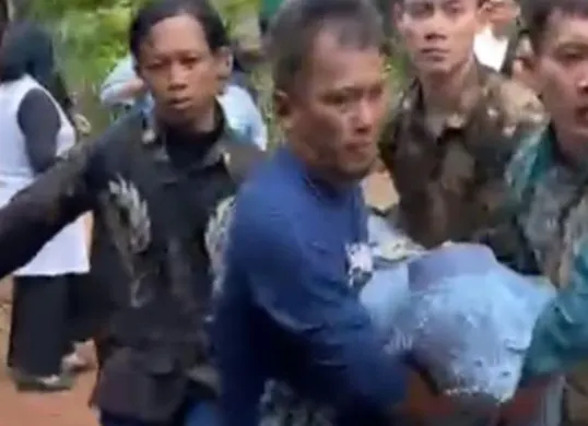 Sejumlah warga membopong istri korban Dadang yang pingsan setelah mengetahui suaminya jatuh dihantam balok kayu oleh preman kampung. (Sumber: Istimewa)