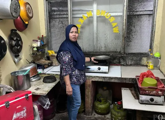 Tuti, ibu rumah tangga di Palmerah, Jakarta Barat, sedang mengecek gas di dapur warung nasi miliknya, Selasa, 21 April 2026. (Sumber: Poskota/Pandi Ramedhan)