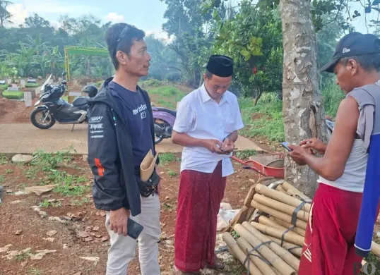 Ketua lingkungan RT 04 RW 04, Herman alias Gareng, (kopiah hitam) bersama warga mencoba mencari informasi ke penggali makam terkait kebenaran informasi viral di TPU Pasir Putih. (Sumber: Poskota/ Angga Pahlevi)