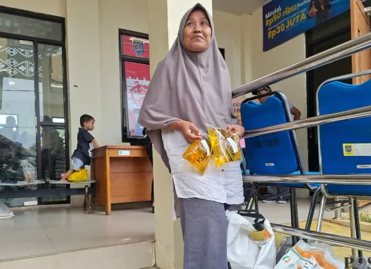 Warga Serua, Nokyani, ibu rumah tangga sangat senang mendapatkan bantuan pangan pemerintah diambil sendiri di kantor Kelurahan Serua. (Sumber: Poskota/Angga Pahlevi)