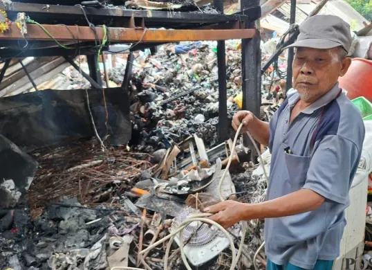 Pengepul barang bekas yang lapaknya ludes terbakar, Nur Wahid mencoba mencari sisa-sisa barang bekas yang masih dapat dijual. (Sumber: Poskota/Angga Pahlevi)