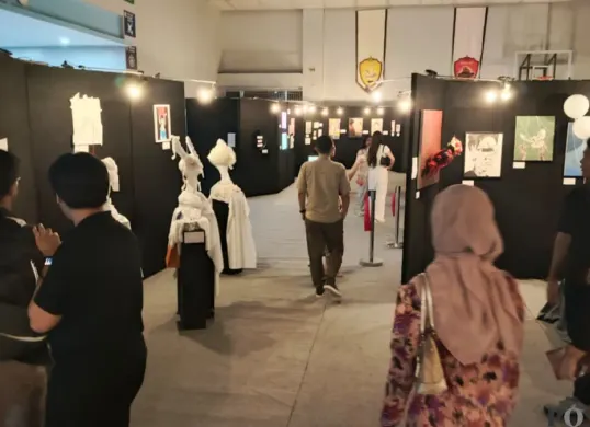 Seorang pengunjung mengamati deretan karya seni siswa BINUS SCHOOL Simprug yang dipamerkan dalam pameran “Intermoven” di aula lantai 8, Kebayoran Lama, Jakarta Selatan, Senin, 9 Februari 2026. (Sumber: Poskota/Ali Mansur)