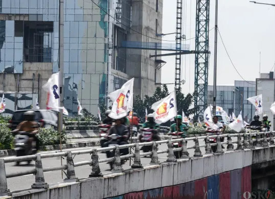 Pengendara sepeda motor melintas di dekat bendera partai politik yang terpasang di Jalan Layang Kemanggisan dan Jalan Pejompongan, Jakarta, Jumat, 6 Februari 2026. (Sumber: Poskota/Bilal Nugraha Ginanjar)