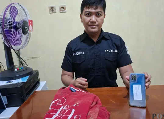 Humas Polsek Cinere, Aiptu Yudho menggelar barang bukti hp Oppo dan jaket sweater pelaku saat digunakan beraksi mencuri disita. (Sumber: Poskota/Angga Pahlevi)