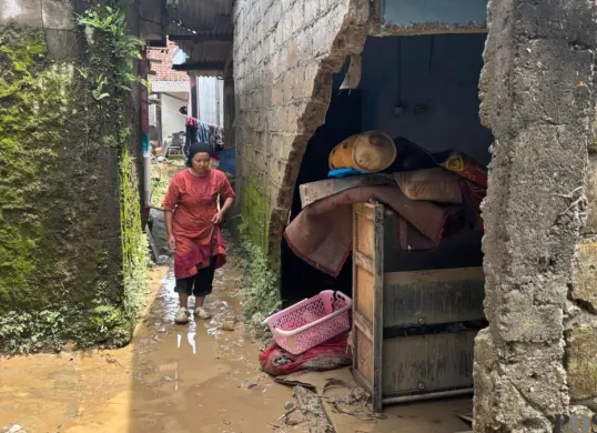 Suryati, 46 tahun tengah bebersih rumahnya yang jebol akibat banjir bandang di Kampung Cicered, Desa Cijayanti, Kecamatan Babakan Madang, Kabupaten Bogor. (Sumber: Poskota/Giffar Rivana)