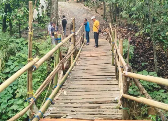 Sejumlah warga di Citaman, Jiput, Pandeglang tengah memperbaiki jembatan sementara. (Sumber: Poskota/Samsul Fatoni)