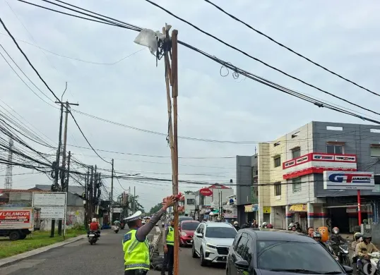 Kabel menjuntai ke jalan raya di Depok ditopang bambu dan kayu. (Sumber: Poskota/ Angga Pahlevi)