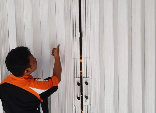 Pegawai toko menunjukkan pintu teralis besi yang dibobol pelaku. (Sumber: Istimewa)