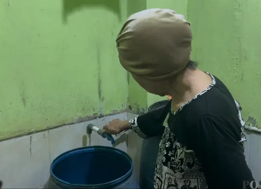 Salah satu warga di Kelurahan Jembatan Besi, Kecamatan Tambora, Jakarta Barat, yang sedang menyalakam kran yang airnya tidak keluar, Jumat, 9 Januari 2026. (Sumber: Poskota/Pandi Ramedhan)