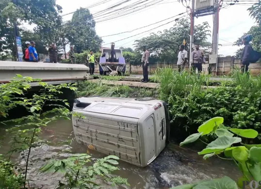 Mobil boks terjun ke Kali Krukut, Jalan Raya Krukut, Kelurahan Gandul, Kecamatan Limo, Kota Depok, Senin, 19 Januari 2026. (Sumber: Poskota/Angga Pahlevi)
