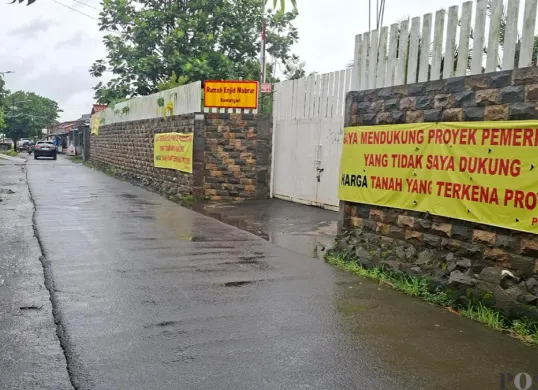 Terpasang tiga spanduk penolakan harga proyek pelebaran tanah di salah satu rumah warga Jalan Enggram, Sawangan, Kota Depok, Rabu, 21 Januari 2026. (Sumber: Poskota/ Angga Pahlevi)