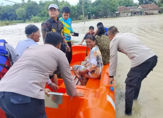 Petugas membantu masyarakat menyebrangi akibat akses jalan terendam. (Sumber: Dok. Polsek Pamarayan)