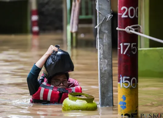 Warga berjalan melintasi banjir yang menggenangi kawasan Kebon Pala, Jakarta Timur, Jumat, 30 Januari 2026 (Sumber: Poskota/Bilal Nugraha Ginanjar)