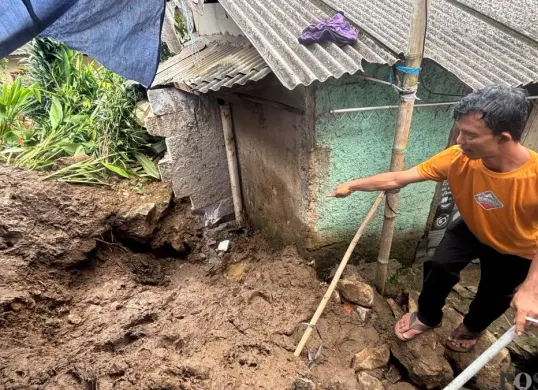 Keponakan korban, Irvan Maulana menunjukkan lokasi lansia yang meregang nyawa akibat longsor TPT di Bogor Selatan. (Sumber: Poskota/Giffar Rivana)