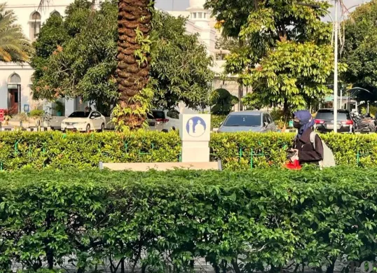 Seorang warga melindungi dirinya dari panas matahari dengan mengenakan jaket dan topi sinar matahari, Sabtu, 14 Maret 2026. (Sumber: Poskota/M. Tegar Jihad)