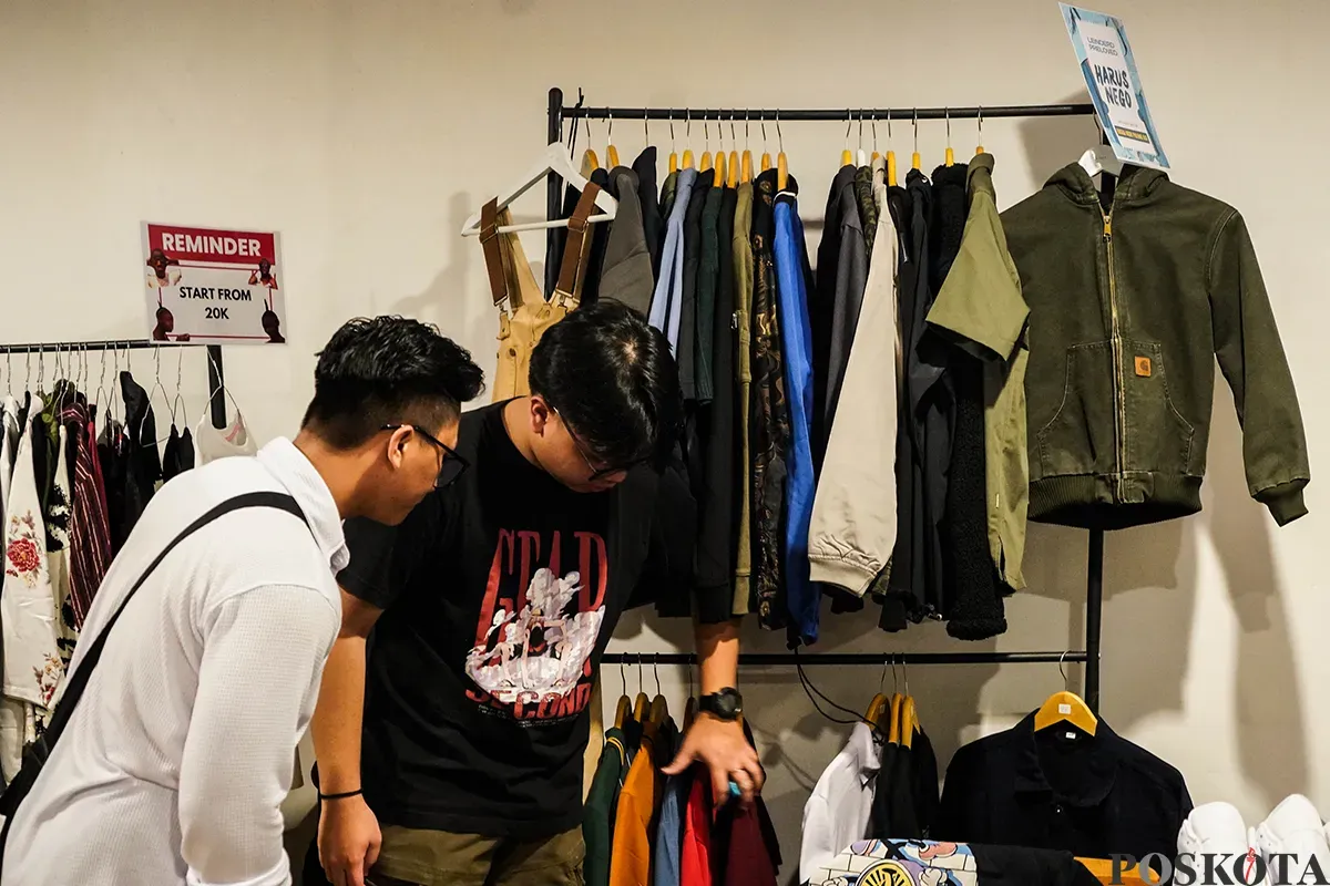 Pengunjung memilah dan memilih aneka merek pakaian bekas atau preloved yang sempat dikenakan oleh sejumlah influencer di lapak penjualan busana di Kuru Ground, Tebet, Jakarta Selatan, Sabtu, 19 April 2025. (Sumber: Poskota/Bilal Nugraha Ginanjar)