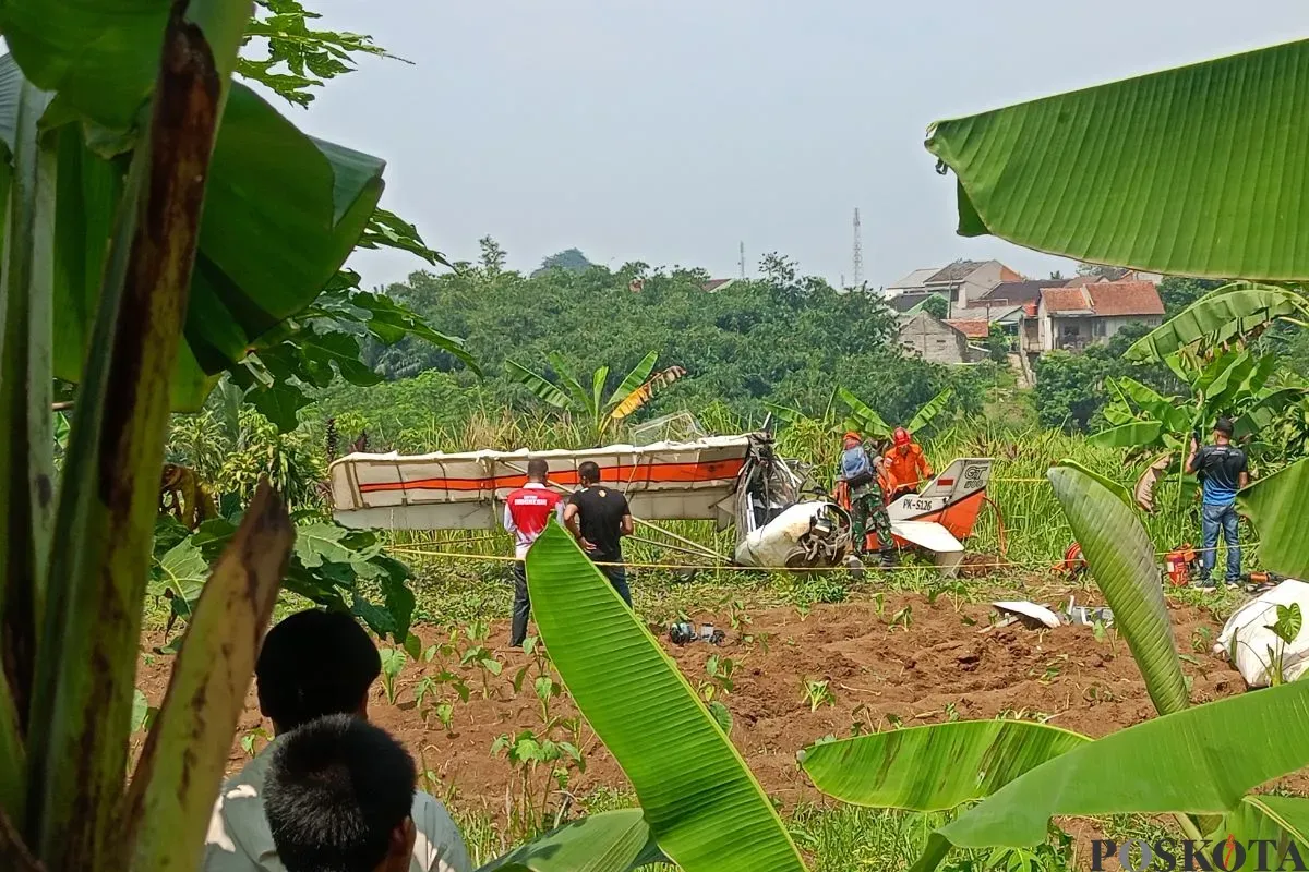 Petugas memotong badan pesawat latih GT 500 PK-S126 yang terjatuh di dekat TPU, Kampung Astana RT 03/01, Desa Benteng, Kecamatan Ciampea, Kabupaten Bogor, Minggu, 3 Agustus 2025. (Sumber: Poskota/Giffar Rivana)