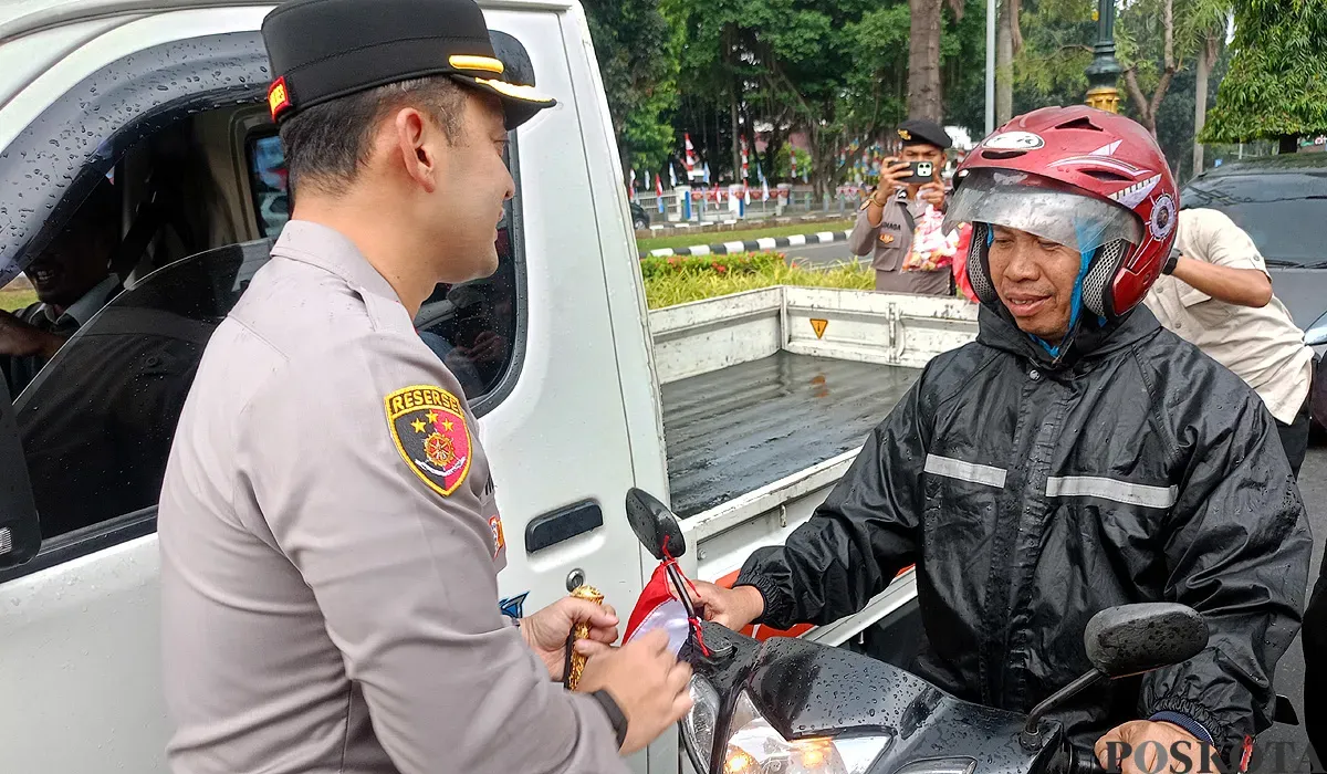 Kapolres Bogor AKBP Wikha Ardilestanto membagikan bendera merah putih kepada pengendara sepeda motor di Jalan Tegar Beriman, Cibinong, Kabupaten Bogor. (Sumber: POSKOTA | Foto: Giffar Rivana)