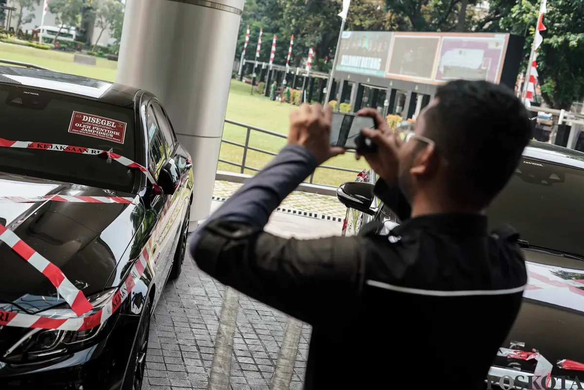 Jurnalis merekam sejumlah mobil sitaan penyidik Jaksa Agung Muda Bidang Tindak Pidana Khusus (Jampidsus) di Kejaksaan Agung, Jakarta, Selasa, 5 Agustus 2025. (Sumber: Poskota/Bilal Nugraha Ginanjar)