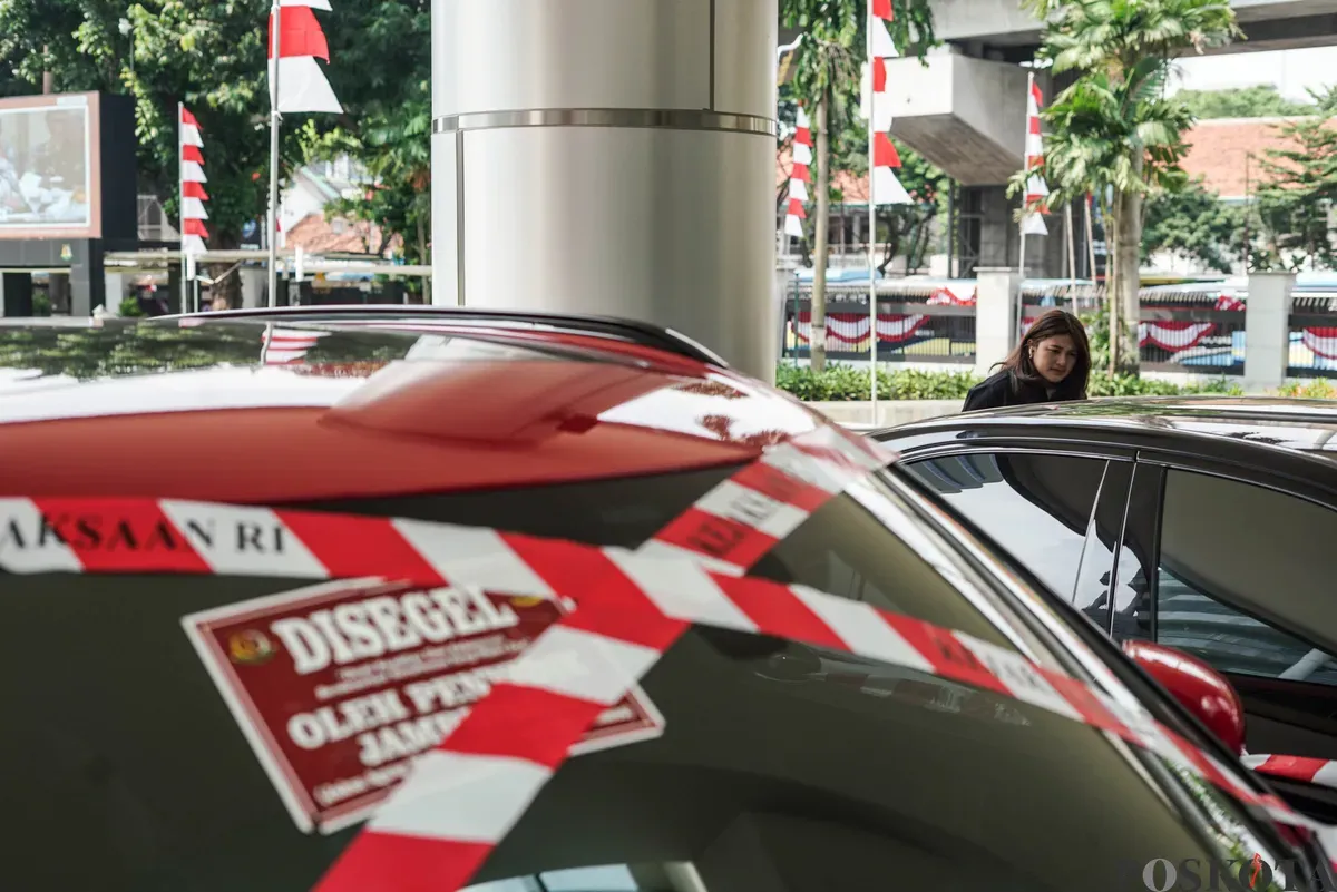 Jurnalis merekam sejumlah mobil sitaan penyidik Jaksa Agung Muda Bidang Tindak Pidana Khusus (Jampidsus) di Kejaksaan Agung, Jakarta, Selasa, 5 Agustus 2025. (Sumber: Poskota/Bilal Nugraha Ginanjar)