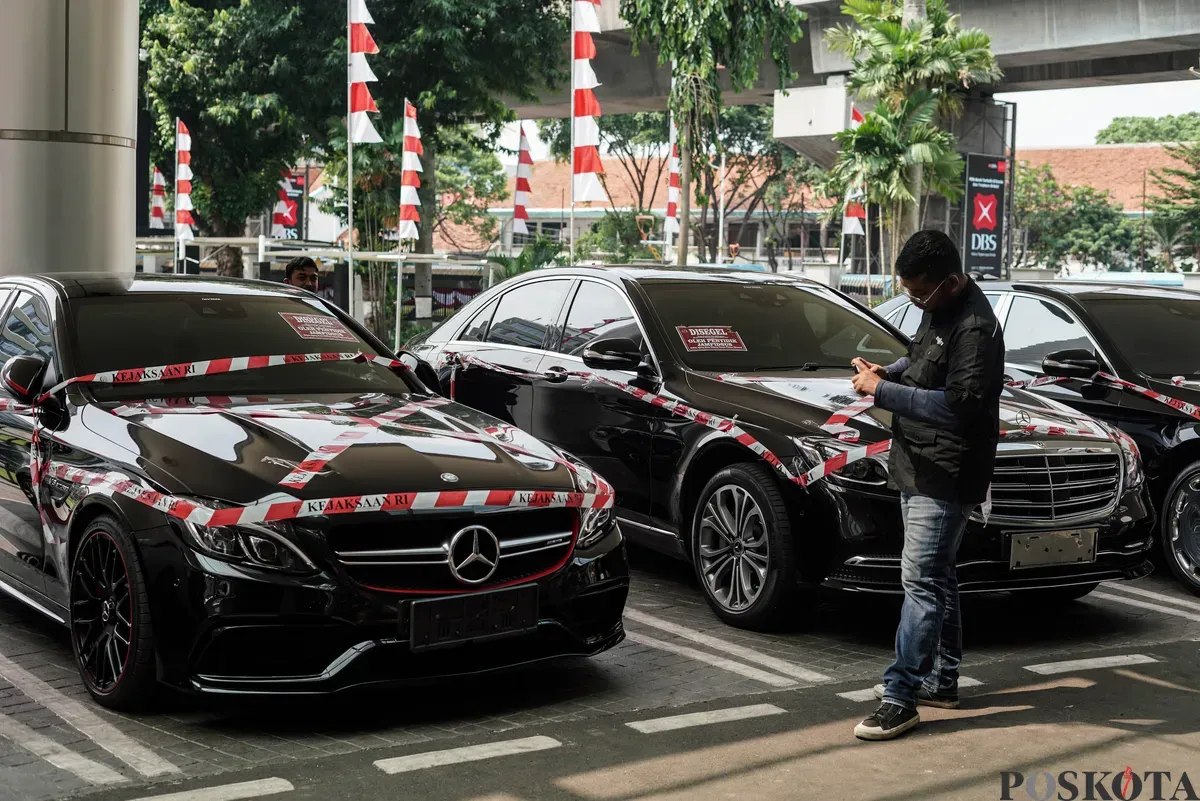 Jurnalis merekam sejumlah mobil sitaan penyidik Jaksa Agung Muda Bidang Tindak Pidana Khusus (Jampidsus) di Kejaksaan Agung, Jakarta, Selasa, 5 Agustus 2025. (Sumber: Poskota/Bilal Nugraha Ginanjar)