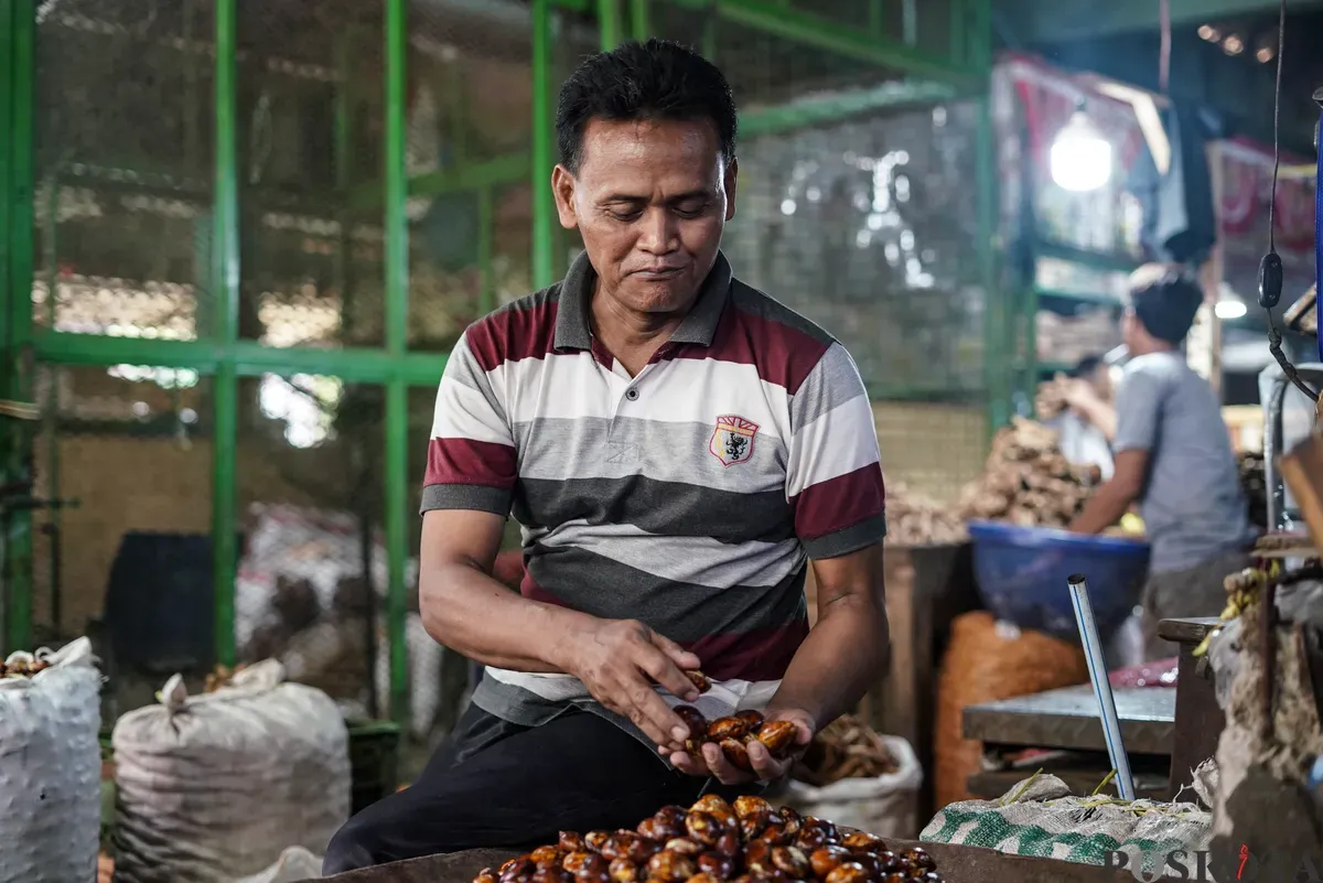 Pedagang jengkol menata buah jengkol di Pasar Induk Kramat Jati dan Pasar Kebayoran Lama, Jakarta, Senin, 11 Agustus 2025. (Sumber: Poskota/Bilal Nugraha Ginanjar)
