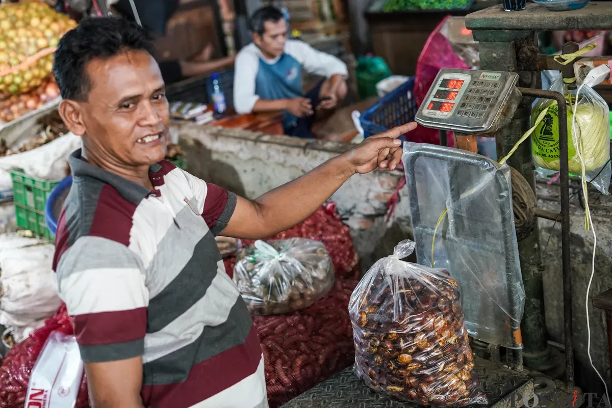 Pedagang jengkol menata buah jengkol di Pasar Induk Kramat Jati dan Pasar Kebayoran Lama, Jakarta, Senin, 11 Agustus 2025. (Sumber: Poskota/Bilal Nugraha Ginanjar)