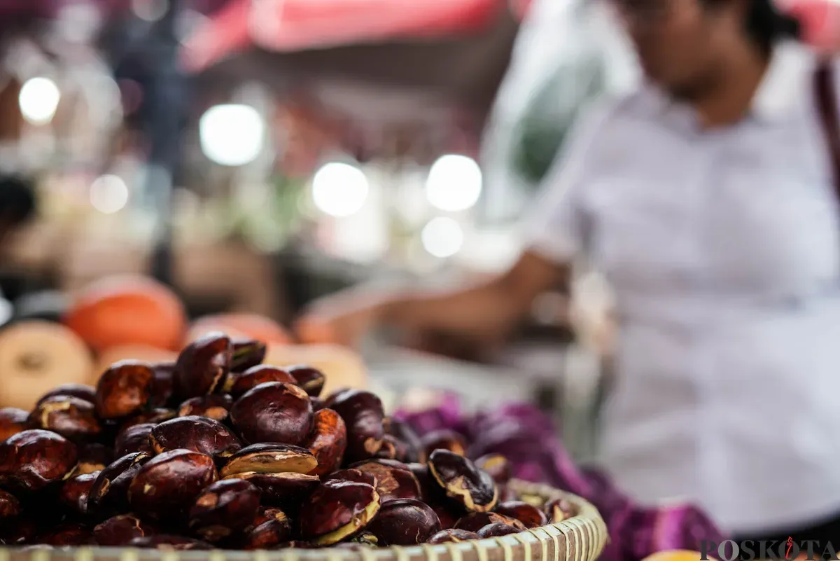 Pedagang jengkol menata buah jengkol di Pasar Induk Kramat Jati dan Pasar Kebayoran Lama, Jakarta, Senin, 11 Agustus 2025. (Sumber: Poskota/Bilal Nugraha Ginanjar)