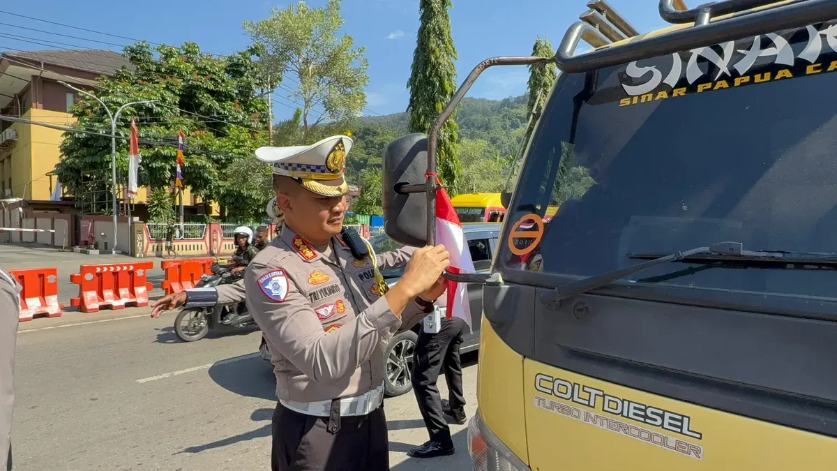 Dirlantas Polda Papua, Kombes Pol Tri Yulianto, membagikan dan langsung memasangkan bendera merah putih kepada supir truk barang di depan kantor Mapolda Papua. (Sumber: Ditlantas Polda Papua)