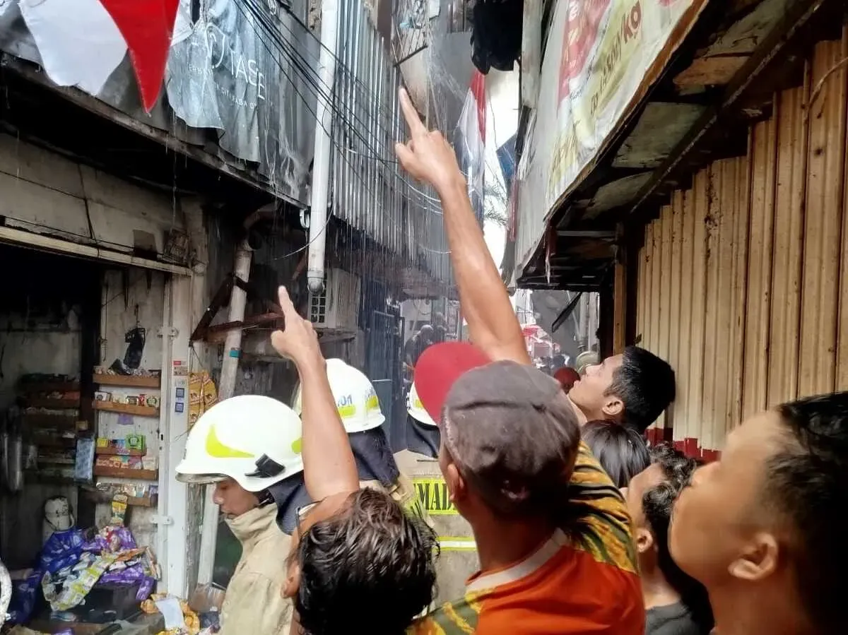 Sejumlah warga menunjuk ke salah satu bangunan rumah dalam insiden kebakaran hebat  di permukiman padat kawasan Tambora, Jakarta Barat, Rabu, 13 Agustus 2025. (Sumber: Damkar)