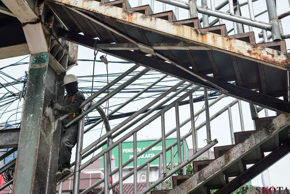 Petugas memperbaiki Jembatan Penyeberangan Orang (JPO) di Jalan Cempaka Putih, Jakarta, Rabu, 13 Agustus 2025. (Sumber: Poskota/Bilal Nugraha Ginanjar)