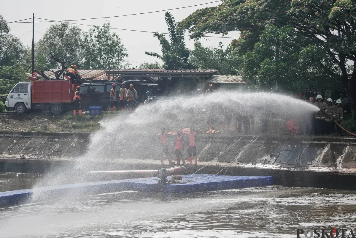 Petugas menyemprotkan air saat simulasi penanganan busa di Pintu Air Weir 3 Marunda, Kanal Banjir Timur (KBT), Jakarta Utara, Rabu, 13 Agustus 2025. (Sumber: Poskota/Bilal Nugraha Ginanjar)