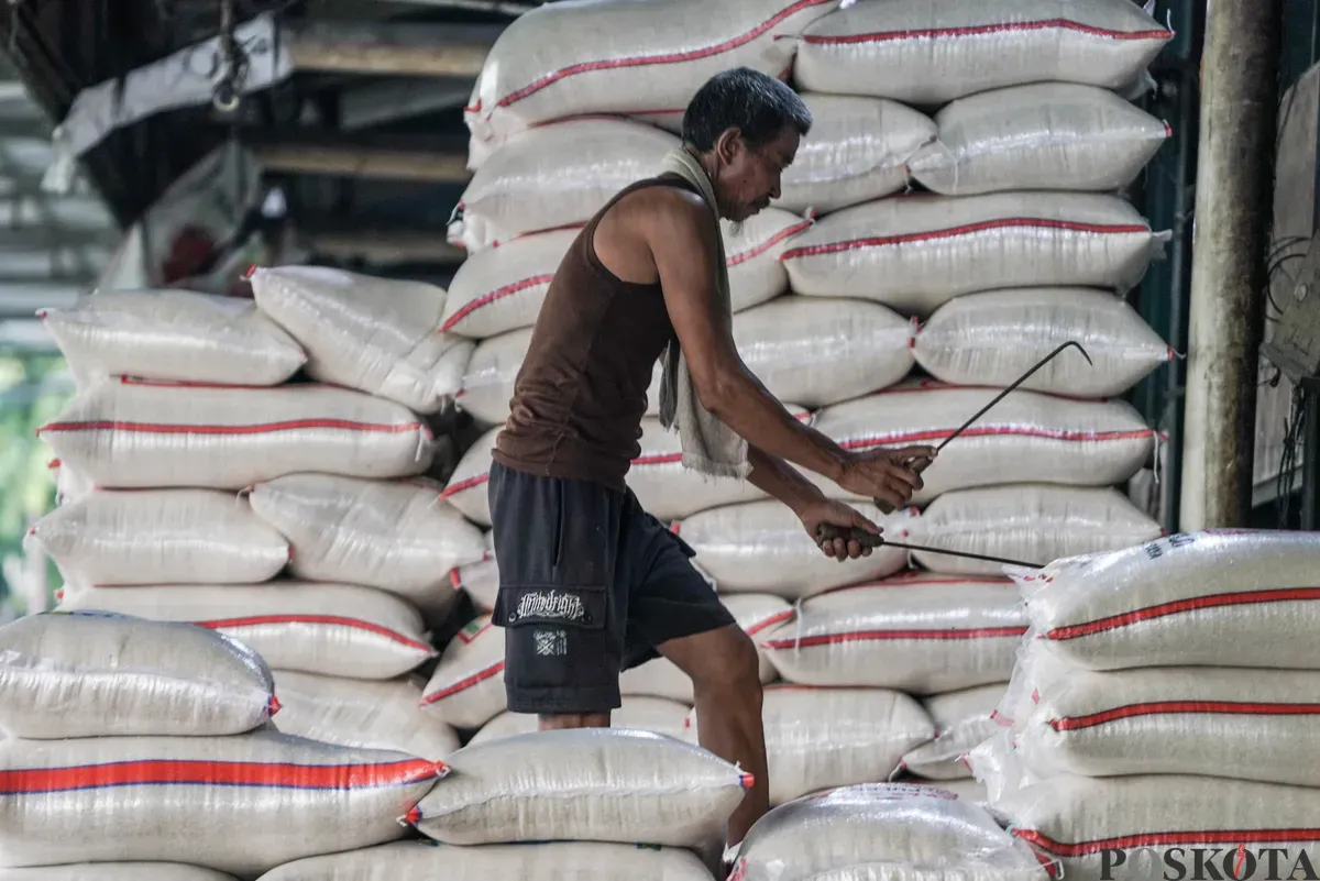 Buruh mengangkut beras di salah agen beras di Pasar Induk Beras Cipinang, Jakarta, Selasa, 12 Agustus, 2025. (Sumber: Poskota/Bilal Nugraha Ginanjar)