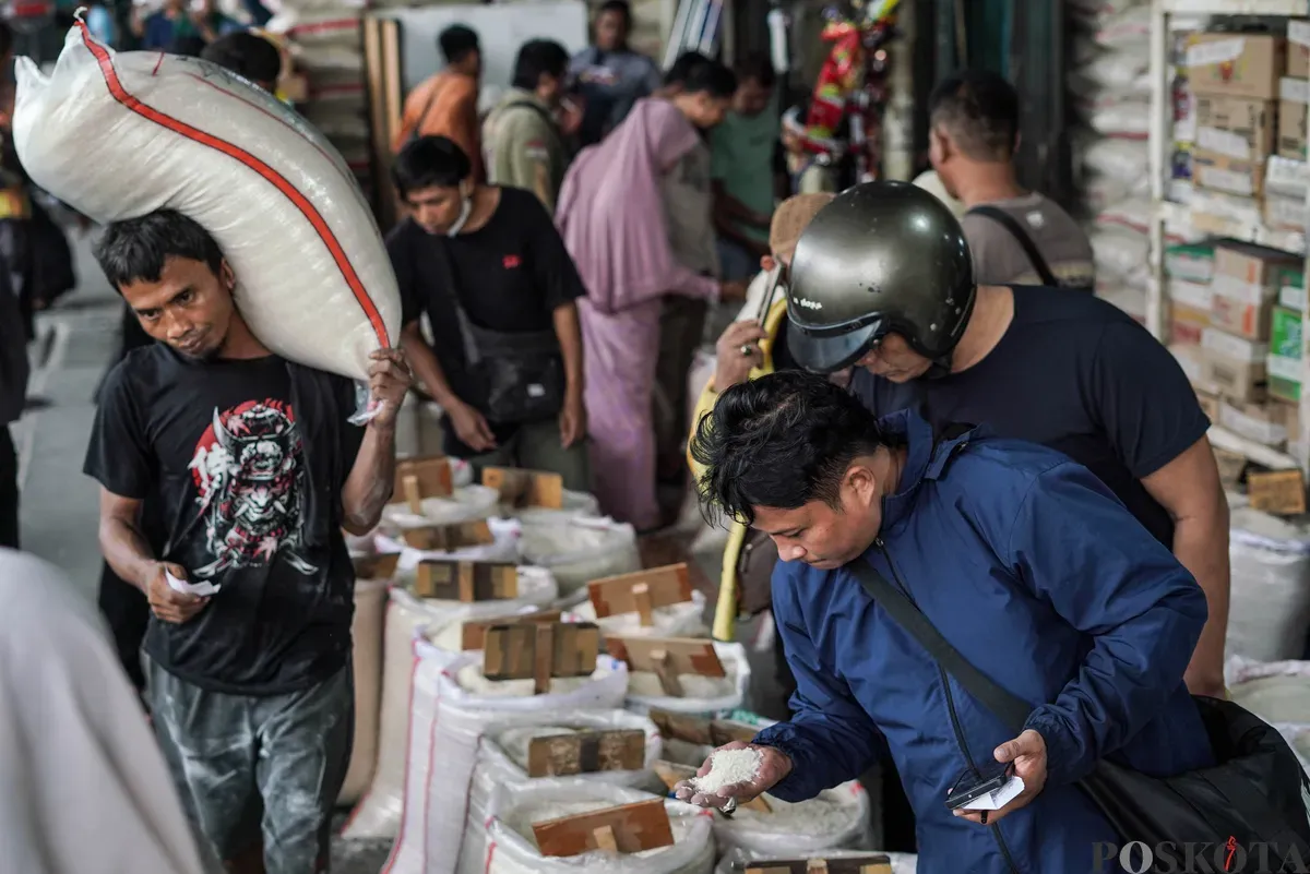 Buruh mengangkut beras di salah agen beras di Pasar Induk Beras Cipinang, Jakarta, Selasa, 12 Agustus, 2025. (Sumber: Poskota/Bilal Nugraha Ginanjar)