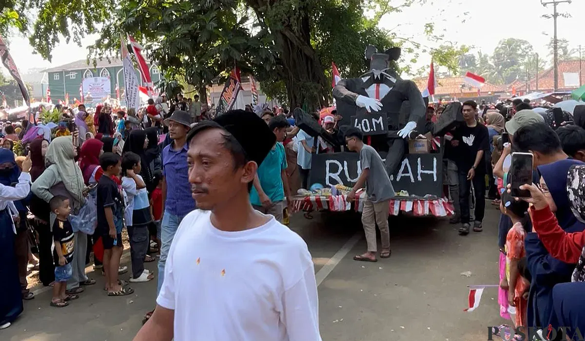 Peserta karnaval 17 Agustus 2025 di Kecamatan Menes, Pandeglang, membawa ornamen tikus berdasi ukuran besar. (Sumber: POSKOTA | Foto: Samsul Fatoni)