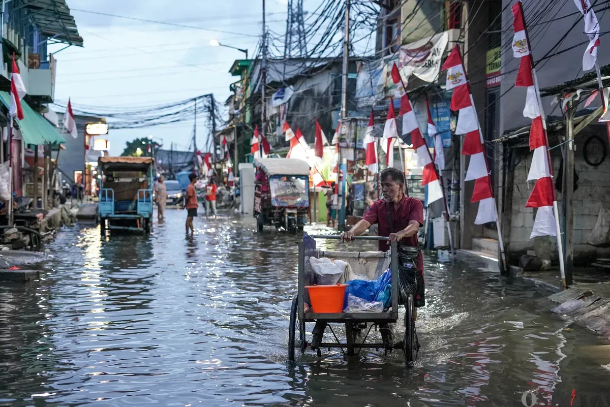 Warga melintasi genangan rob di Muara Angke, Jakarta Utara, Senin, 18 Agustus 2025. (Sumber: Poskota/Bilal Nugraha Ginanjar)
