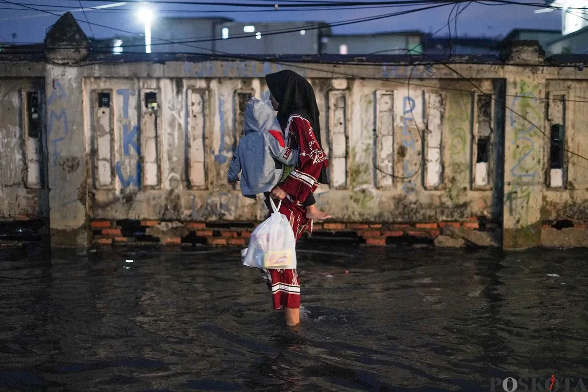 Warga melintasi genangan rob di Muara Angke, Jakarta Utara, Senin, 18 Agustus 2025. (Sumber: Poskota/Bilal Nugraha Ginanjar)