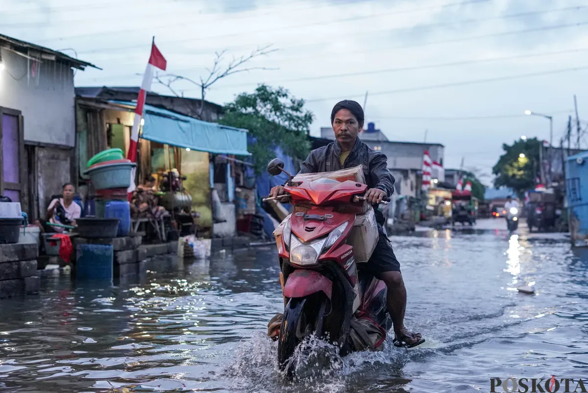 Warga melintasi genangan rob di Muara Angke, Jakarta Utara, Senin, 18 Agustus 2025. (Sumber: Poskota/Bilal Nugraha Ginanjar)