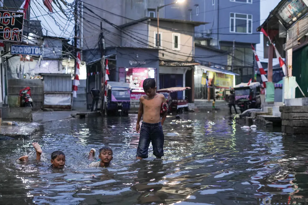 Warga melintasi genangan rob di Muara Angke, Jakarta Utara, Senin, 18 Agustus 2025. (Sumber: Poskota/Bilal Nugraha Ginanjar)