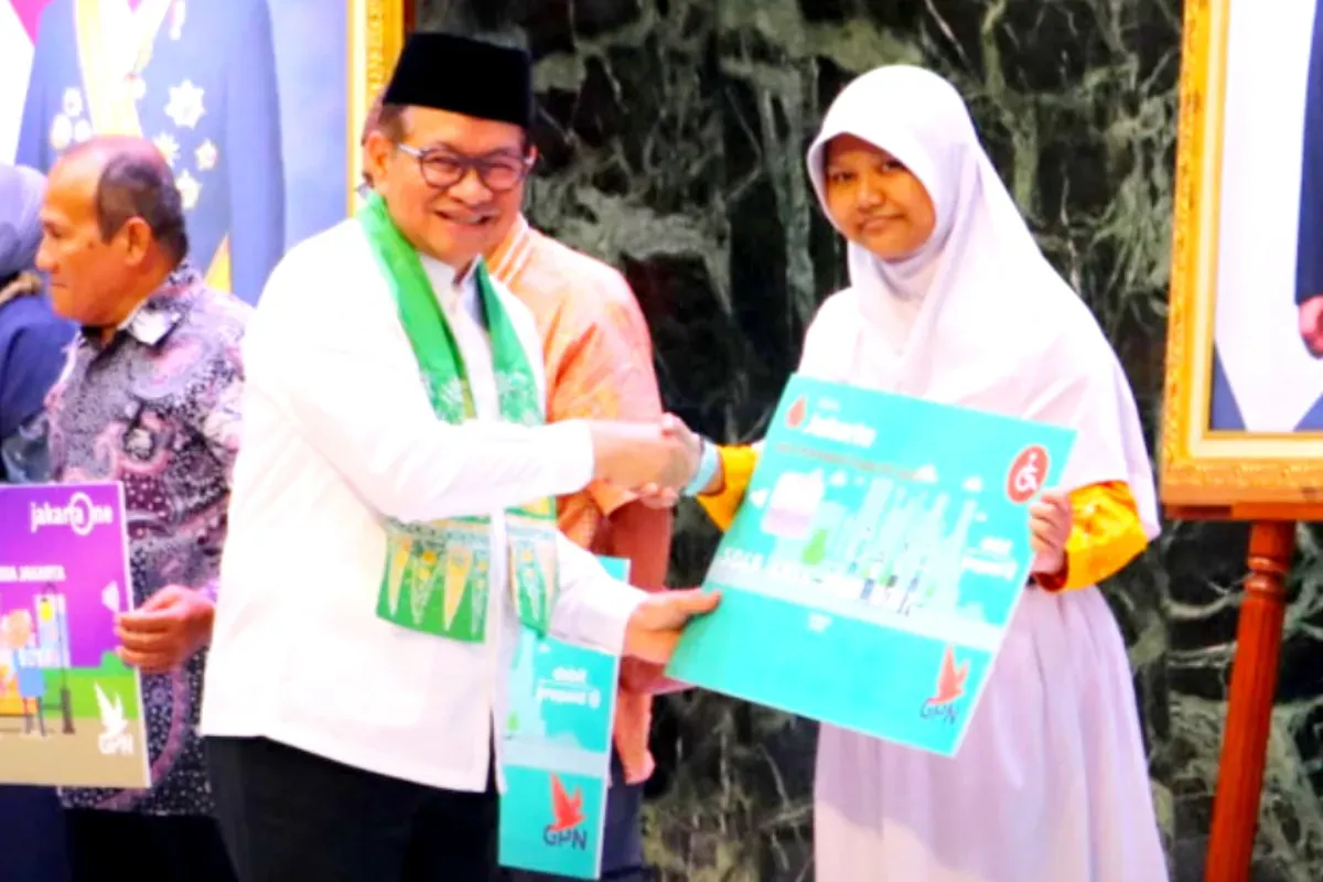 Potret Gubernur DKI Jakarta, Pramono Anung (kiri) yang memberikan secara simbolis kartu rekening untuk penerima baru bansos Kartu Anak Jakarta (KAJ). (Sumber: Dinas Sosial Pemprov DKI Jakarta)