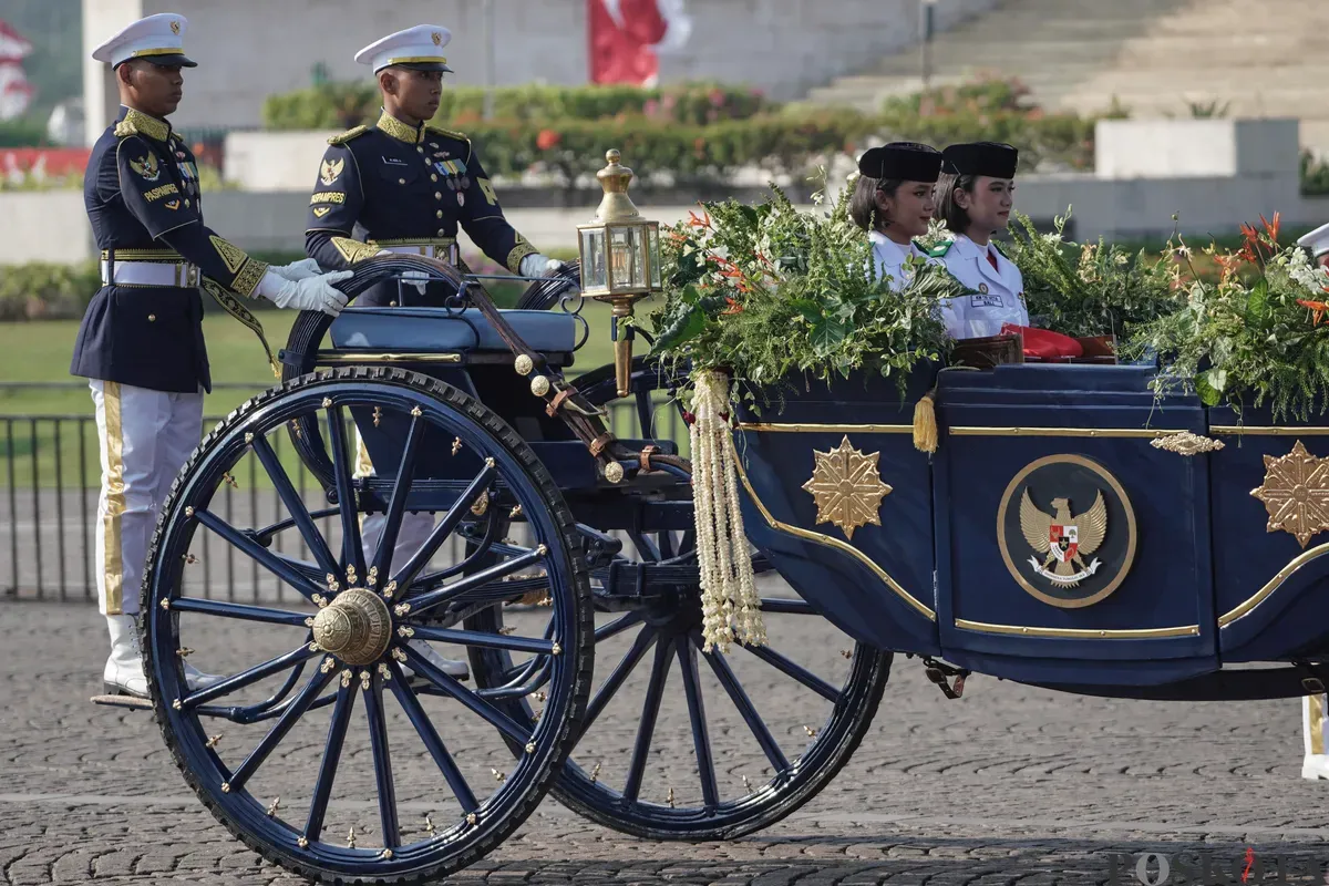 Purna Paskibraka Duta Pancasila 2024, Kirana Ashawidya Baskara dan Ni Komang Tri Setia membawa baki Bendera Pusaka Merah Putih dan Teks Proklamasi saat menaiki Kereta Kencana Garuda Prabayeksa pada Kirab Merah Putih HUT ke-80 Republik Indonesia di Monas, Jakarta, Minggu, 17 Agustus 2025 (Sumber: Poskota/Bilal Nugraha Ginanjar)
